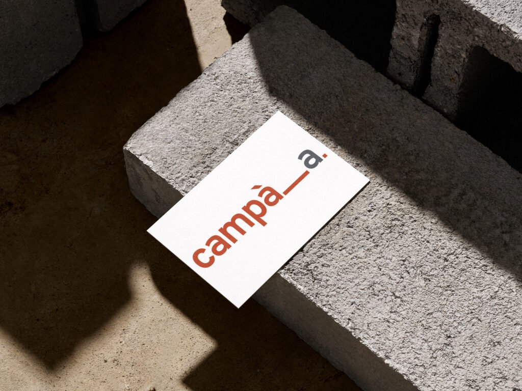 Photo de la carte de visite issue d'un mockup incluant le logotype de l'entreprise d'Architecture intitulée Campà A et située en Corse. Elle est posée à plat sur un bloc de béton.